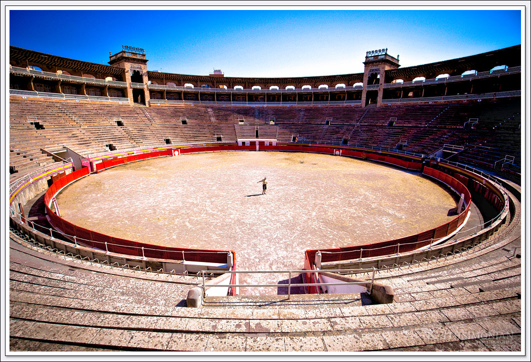 A tourist is pretending to be bullfighting in the Baleares Coliseu Bullring in Palma de Mallorca Spain
