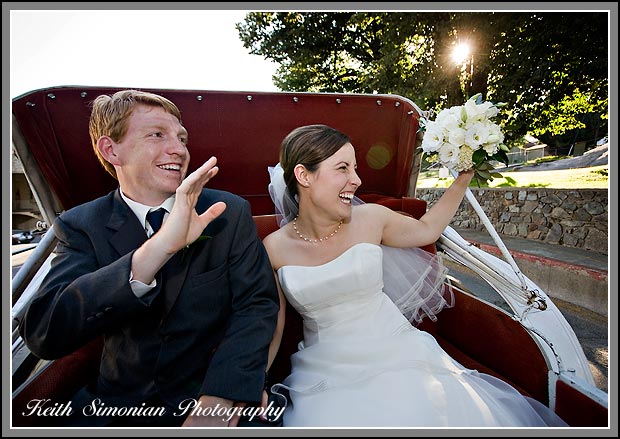 As they ride in horse drawn carriage the bride and groom wave to guests
