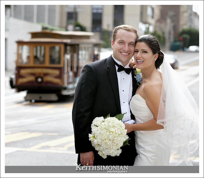 The Bride and Groom pose in front of passing cable car on California Street in San Francisco