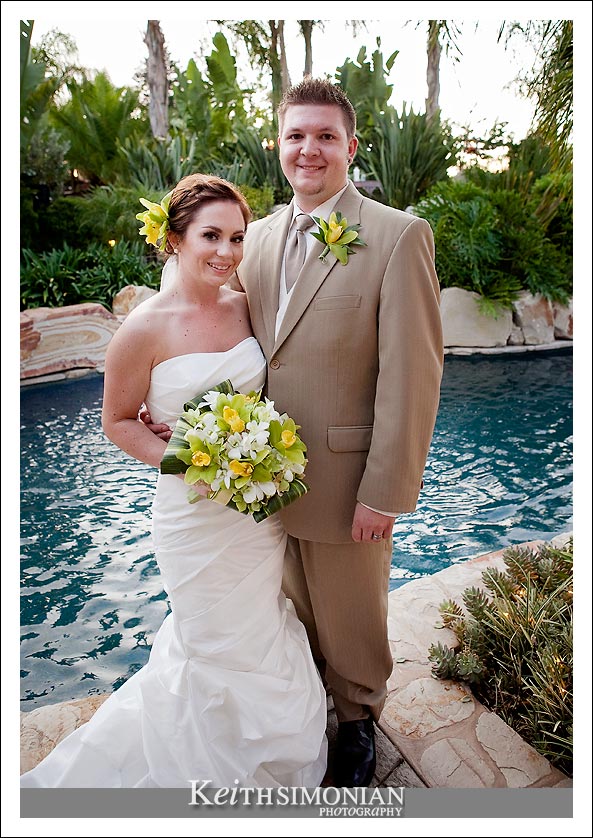 The bride and groom pose in front of the swimming pool