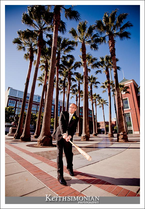 The groom takes a few swings of the bat outside AT&T park in front of the palm trees, home of the San Francisco Giants