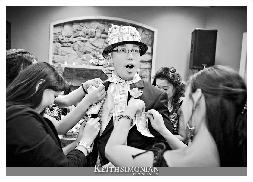 Black and white photo of guest pinning money on groom during the money dance