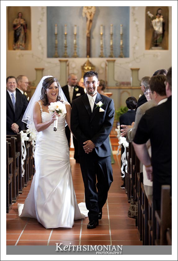 Bride and groom walk down the aisle after just getting married at the San Carlos Cathedral in Monterey, CA