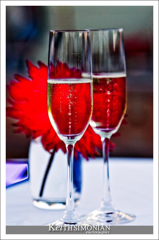 The red flower behind the champagne glasses give the champagne a red color