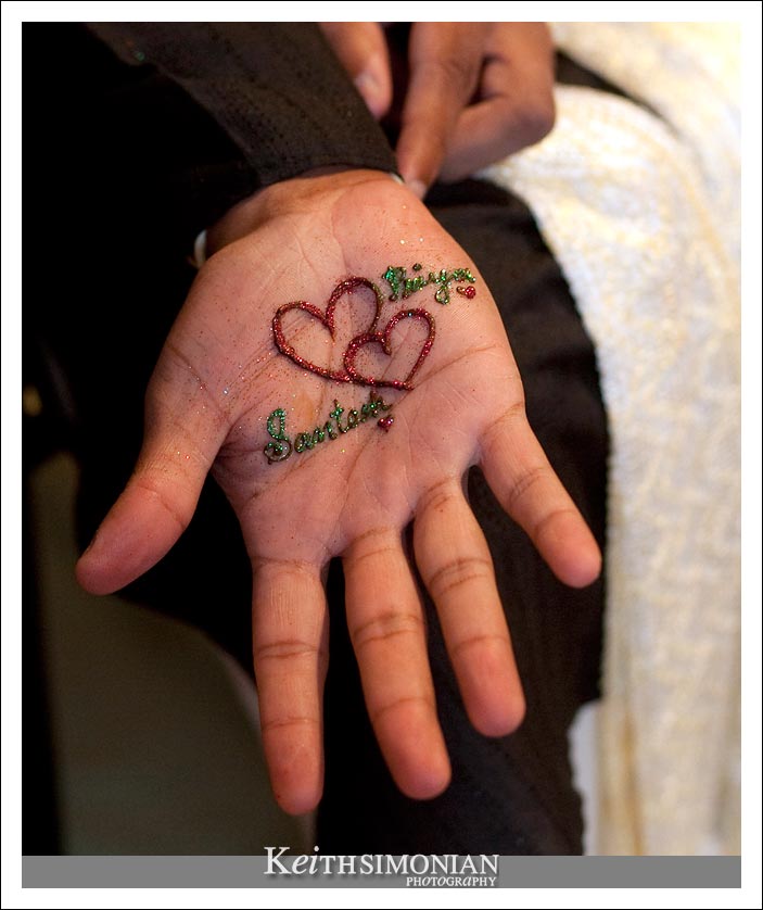 Photo of grooms hand with two hearts made with henna temporary skin decoration