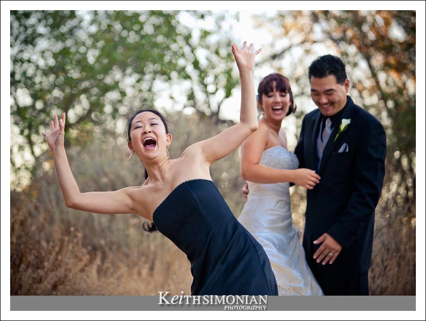 One of the bridesmaids has fun in front of the bride and groom