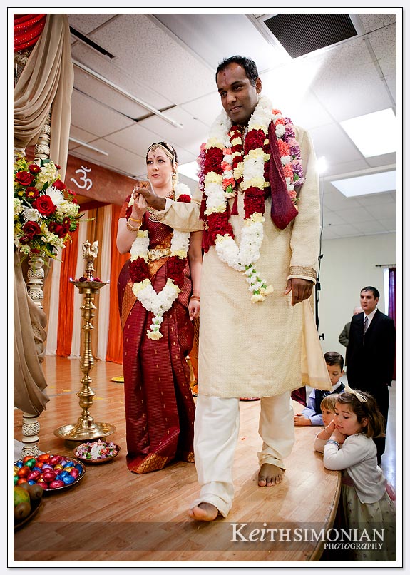 During the Laaja Homam ( offering of puffed rice to Agni ) the bride and groom walk around the sacrad fire during their South Indian Hindu wedding ceremony at Shiva-Vishnu Temple in Livermore, California