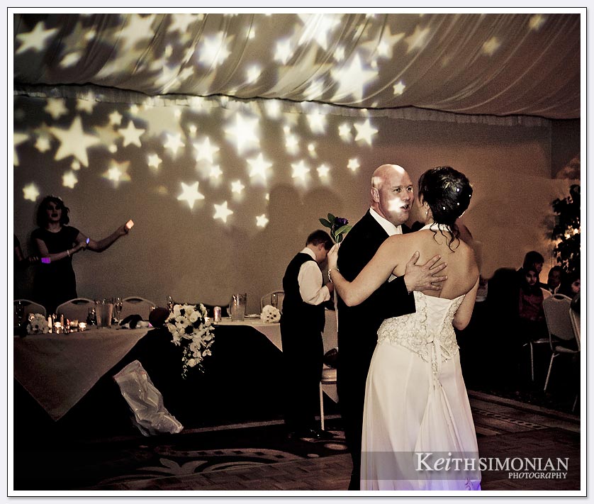 Stars are projected on the ceiling as the bride and groom share their first dance