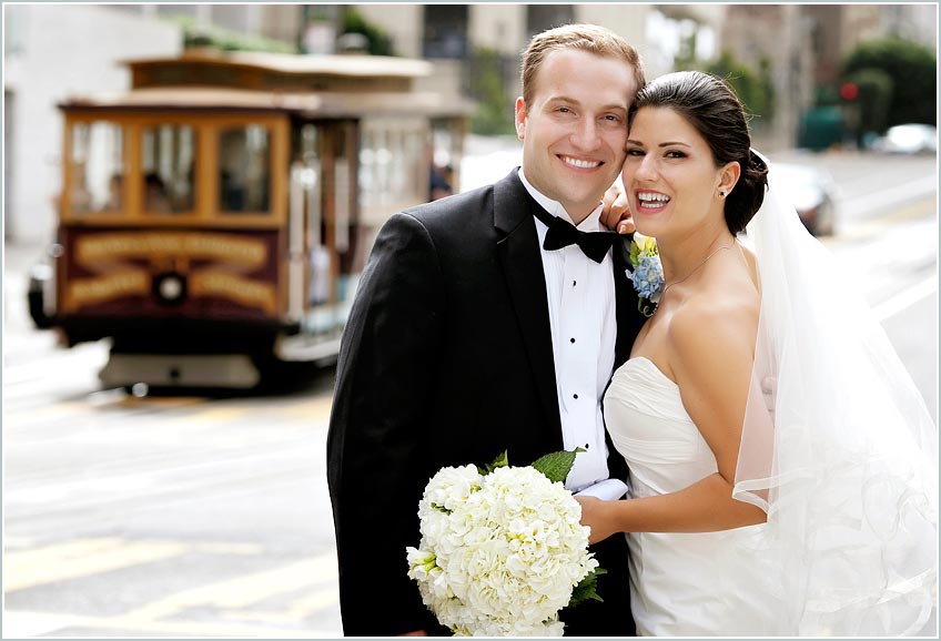 The bride and groom pose in front of San Francisco landmark cable car