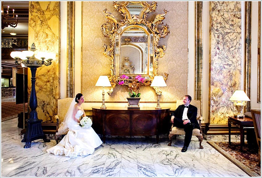 The bride and groom relax in elegant lobby of the Fairmont Hotel in San Francisco, CA