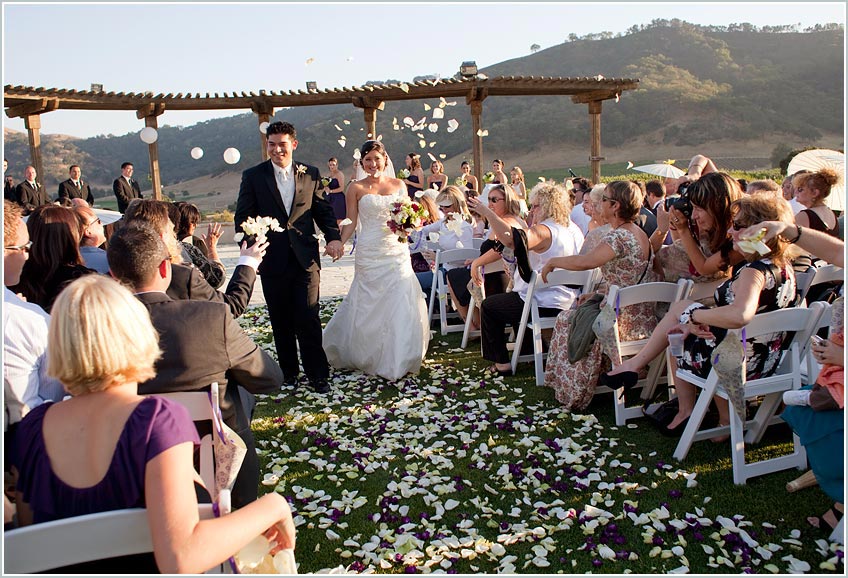 Guests toss flower pedals during wedding ceremony