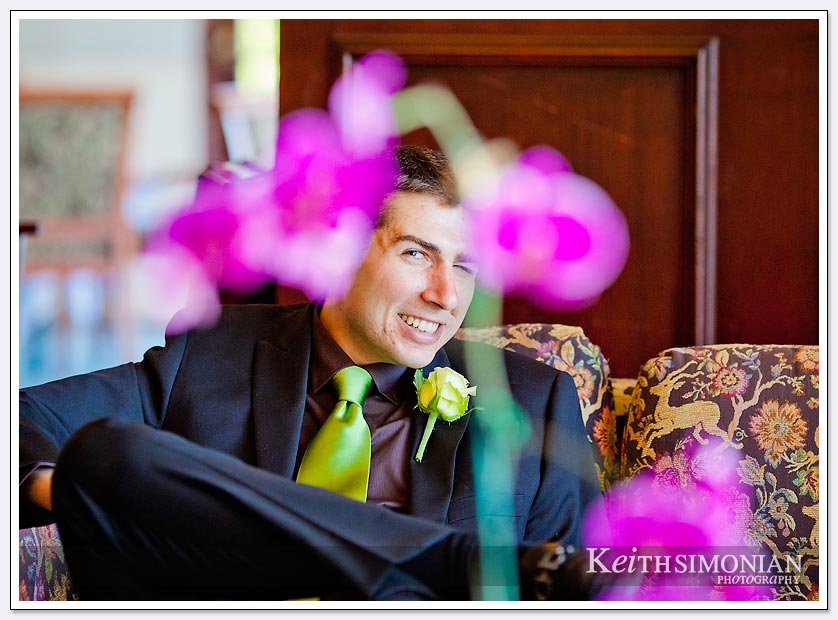 One of the groomsmen is photographed as he is framed by wedding flowers