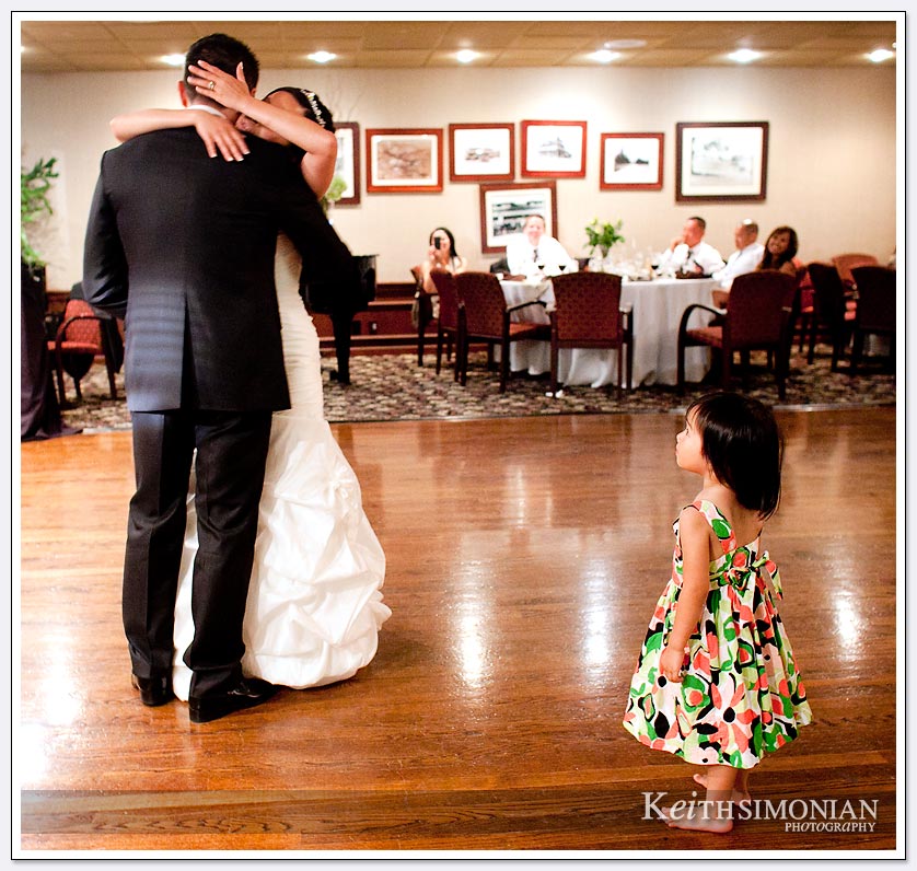 While the bride and groom enjoy their first dance a child comes closer for a better view