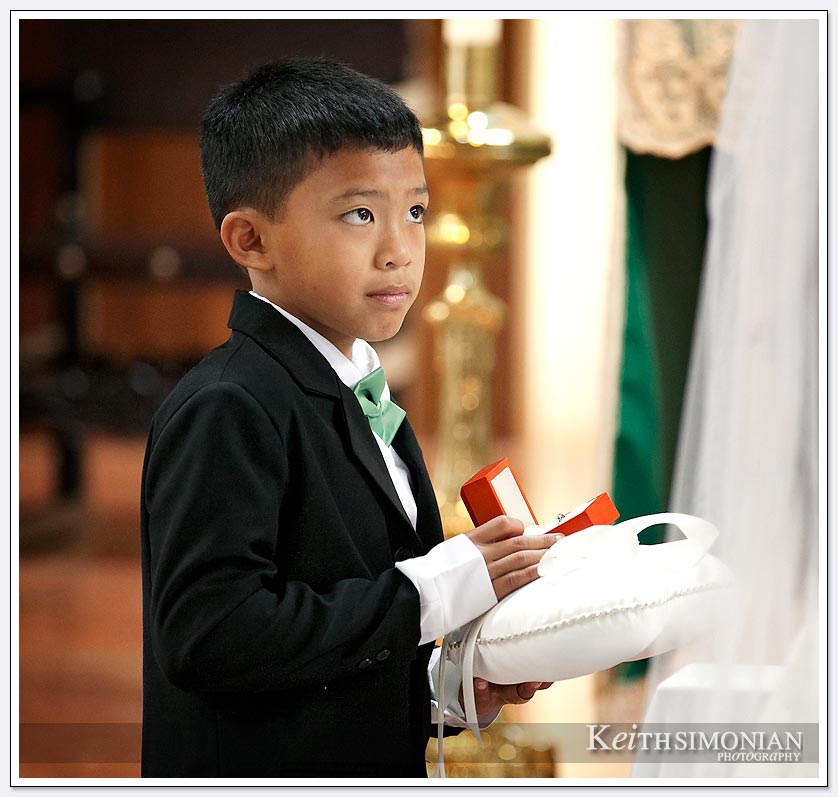 Ring bearer wearing tux waiting to hand over the rings