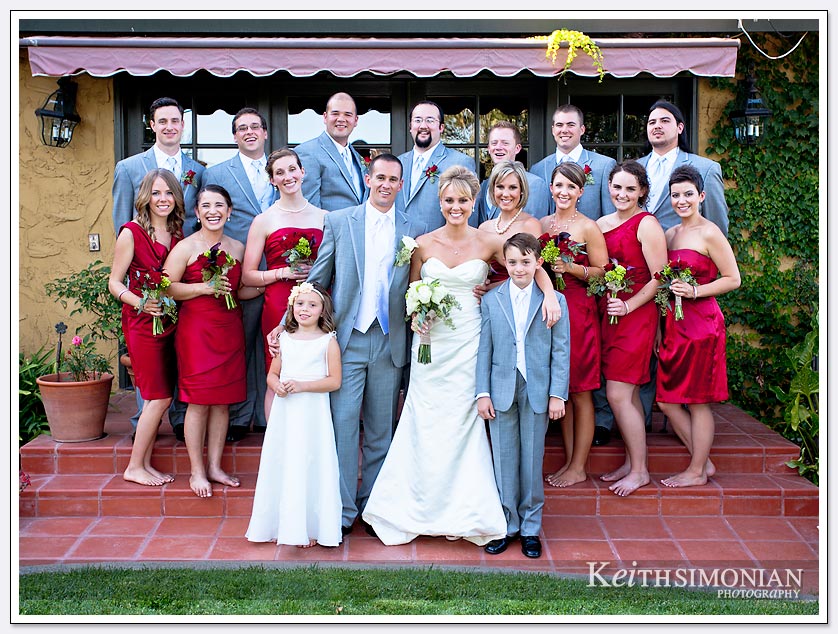 Bridesmaids wearing red dresses and groomsmen in gray tuxedos for the formal bridal party photo