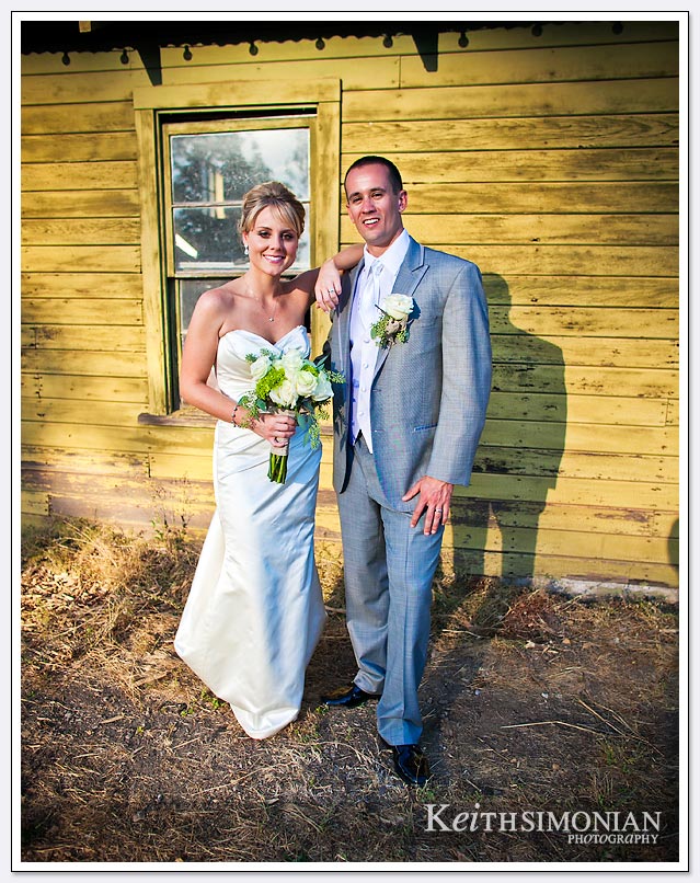 The setting sun shown on the bride and groom in front of the rustic wood building