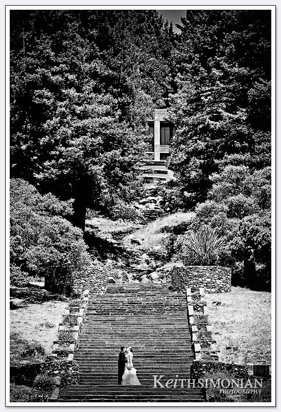 The bride and groom pose near the bottom of the 242 step granite staircase at Joaquin Miller park in Oakland, CA