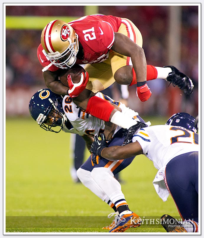 Frank Gore appears to leap over #21 Major Wright of the Chicago Bears in a Monday Night Football match up