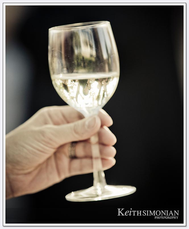 A glass of white wine that shows the reflections of other guests during the wedding reception at the BR Cohn winery