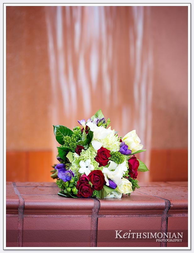 The bride's bouquet sits in front of the water fall by the red brick