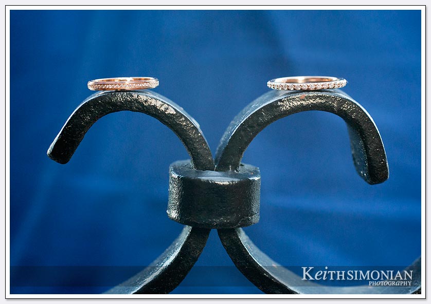 The brides wedding rings sits atop the gate with wonderful blue background
