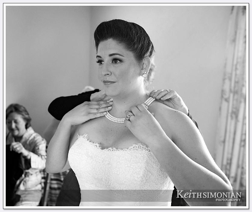 The bride puts on her pearl necklace before her wedding at the Clos La Chance winery in San Martin
