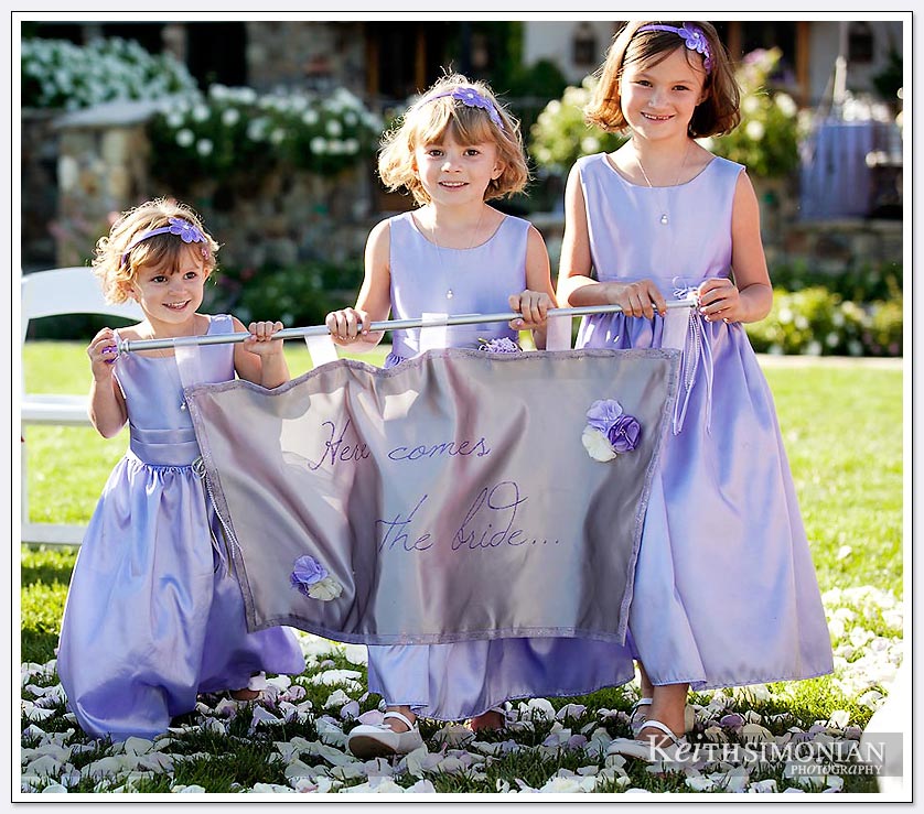 Three girls carry sign that says here comes the bride