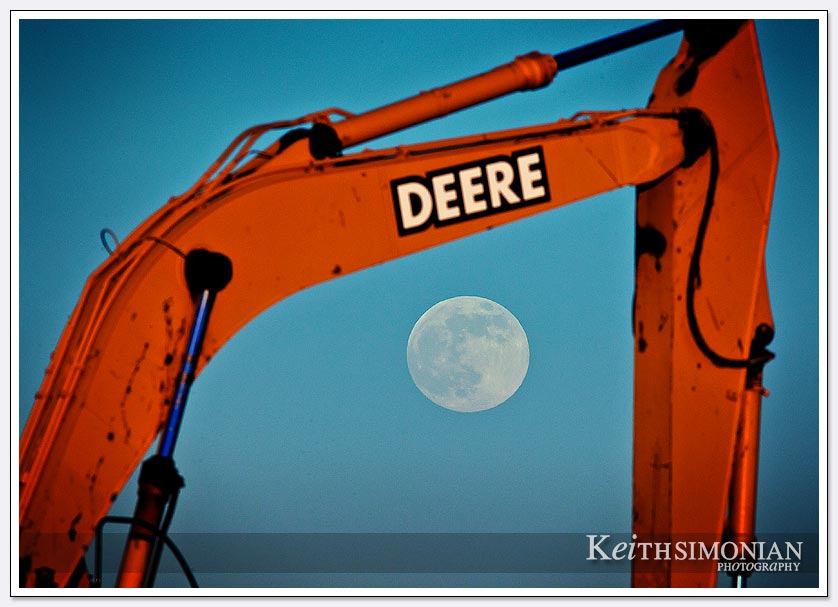 The 2013 supermoon rises in the early evening sky behind a John Deere 270lc crawler excavator
