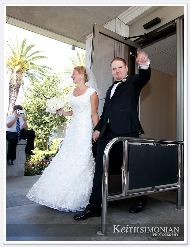 The bride and groom walk out from the Oakland temple to greet family and guests after getting married
