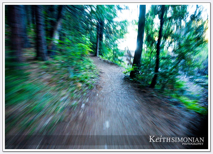 A steady hand and slow shutter speed cause the blurring effect of the trail by a bike rider