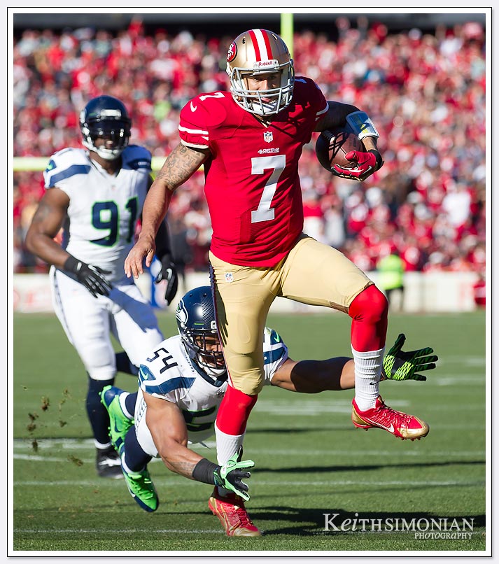 SAN FRANCISCO, CA - DECEMBER 08: Colin Kaepernick #7 of the San Francisco 49ers running with the ball tries to leap away from Bobby Wagner #54 of the Seattle Seahawks during the first quarter at Candlestick Park on December 8, 2013.