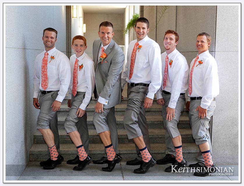 The groom and groomsmen pose for picture showing their matching socks outside Oakland LDS temple