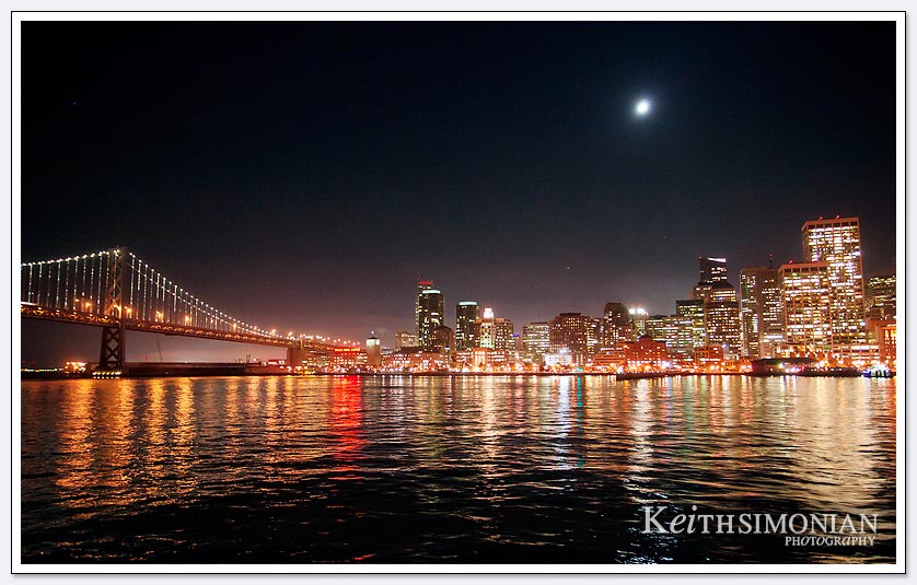 The moon sets over the San Francisco skyline and Bay Bridge