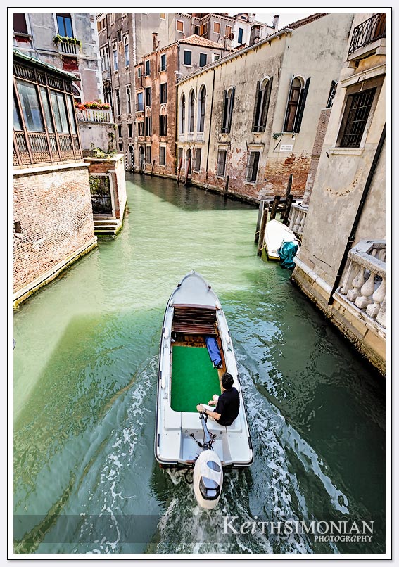 A boat passes under one of the many bridges that connect the islands of Venice, Italy.
