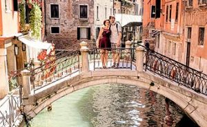 One of the many bridges in Venice Italy provides a romantic backdrop for a young couple.