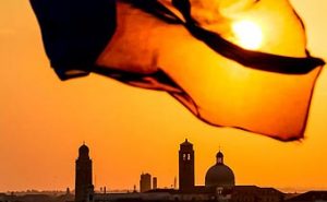 The sun rises over Venice Italy with the cruise ship's flag in front