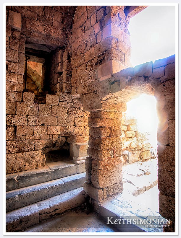 Sunlight steaming through the ancient ruins the make up the Acropolis of Lindos, Greece