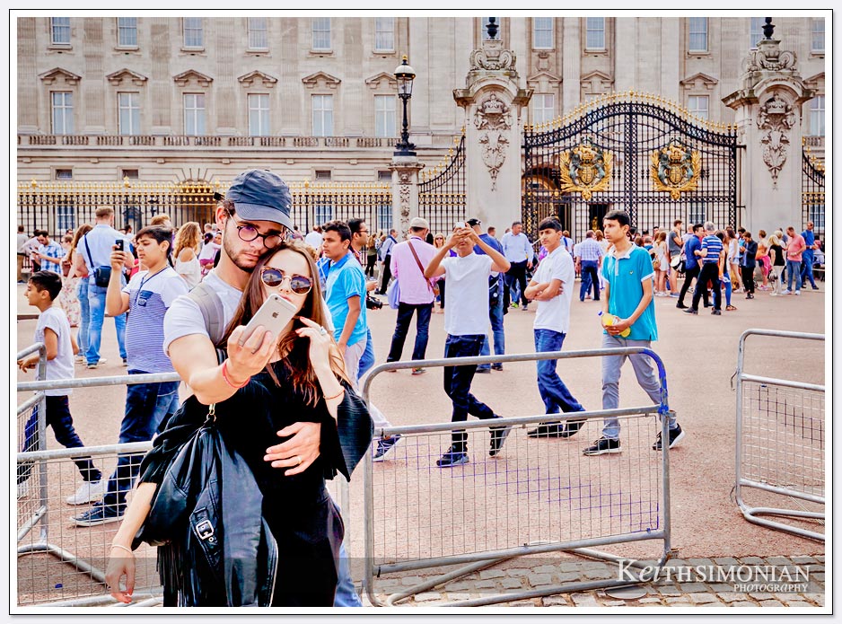 The many,many tourists taking photos outside Buckingham Palace in London England.