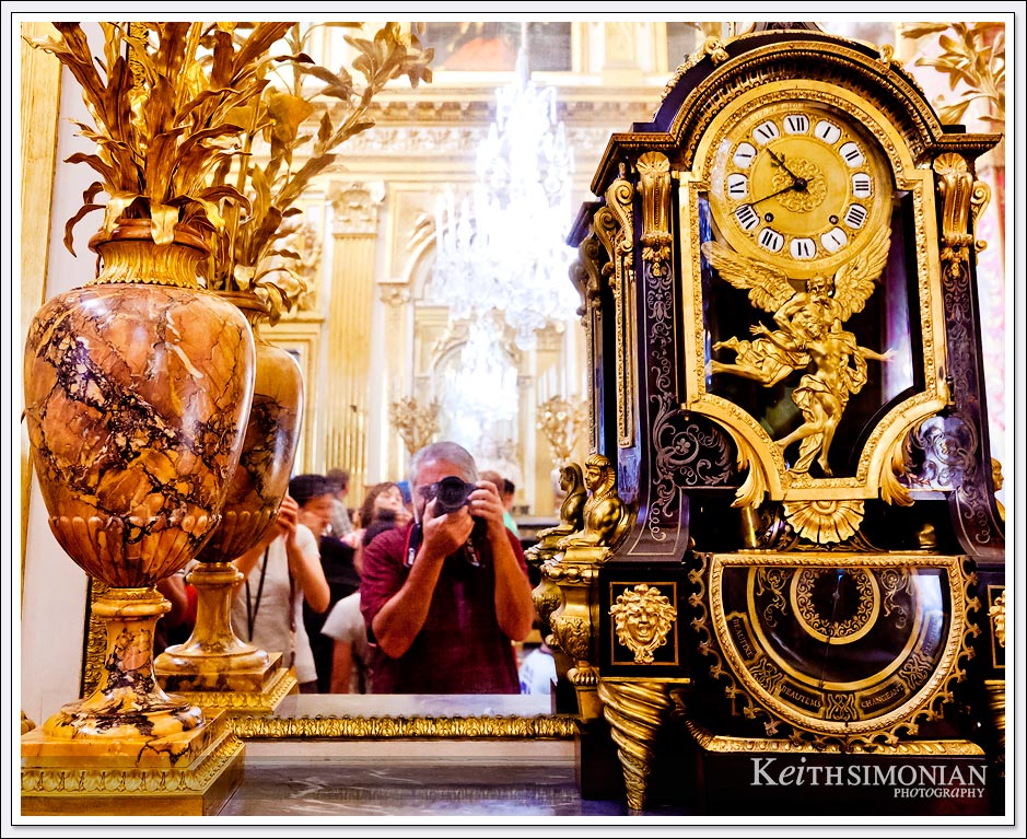 The palace of Versailles - elegant clock and vase with photographer's reflection in the mirror.