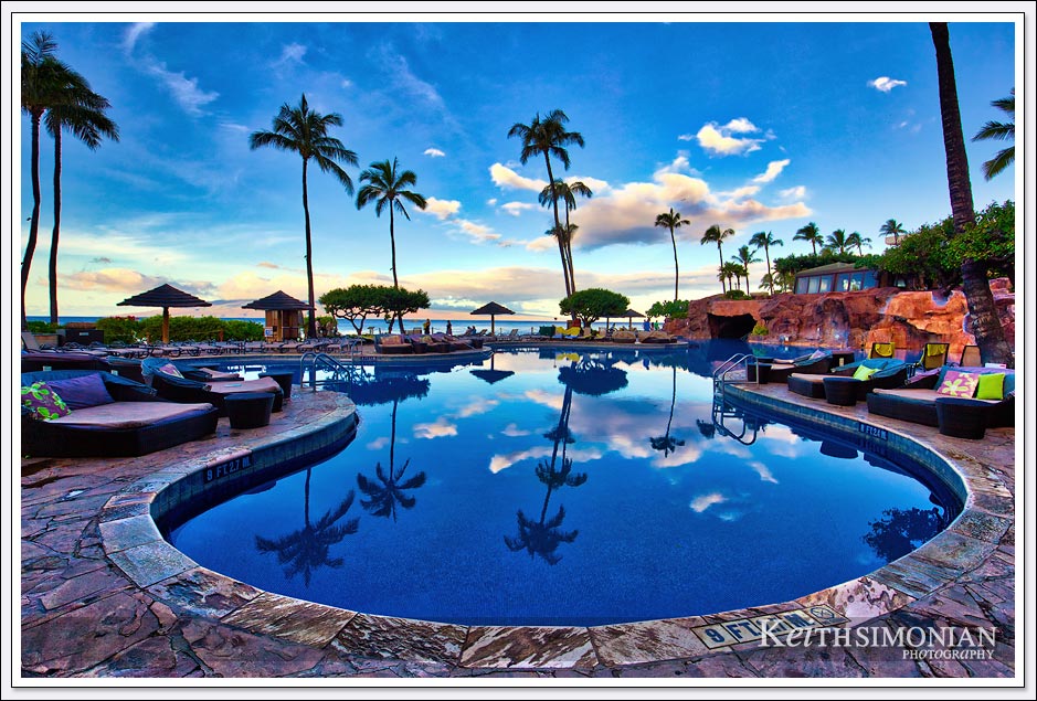 The clouds and palm trees reflect in the swimming pool of the Hyatt Regency Maui Resort and Spa in Maui Hawaii
