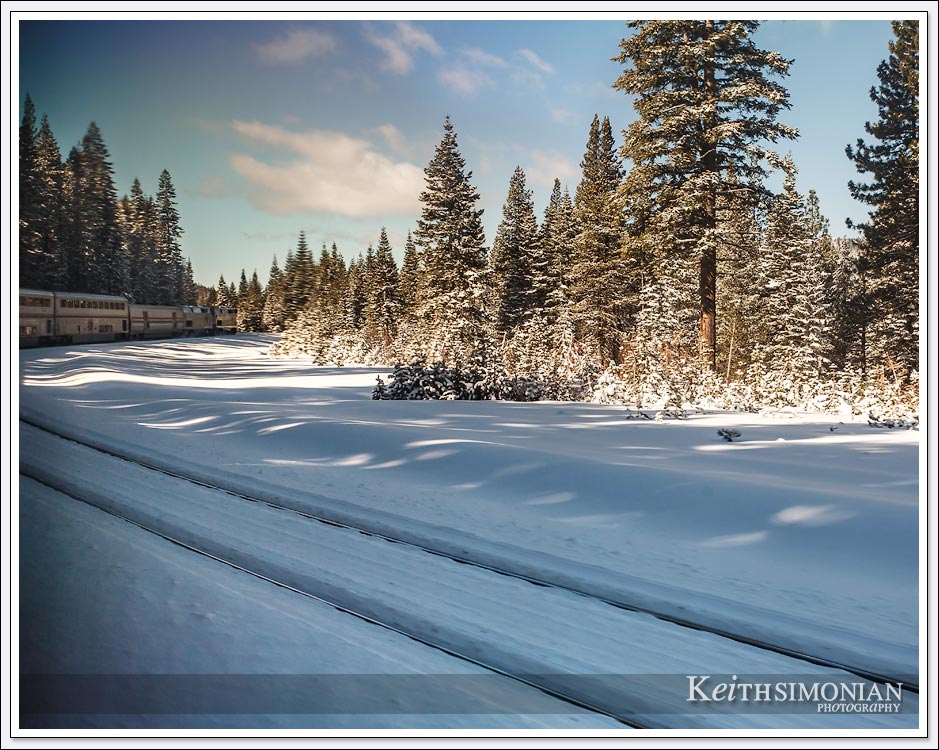 A bend in the tracks gives a view of the lead Amtrak cars passing through the snow.