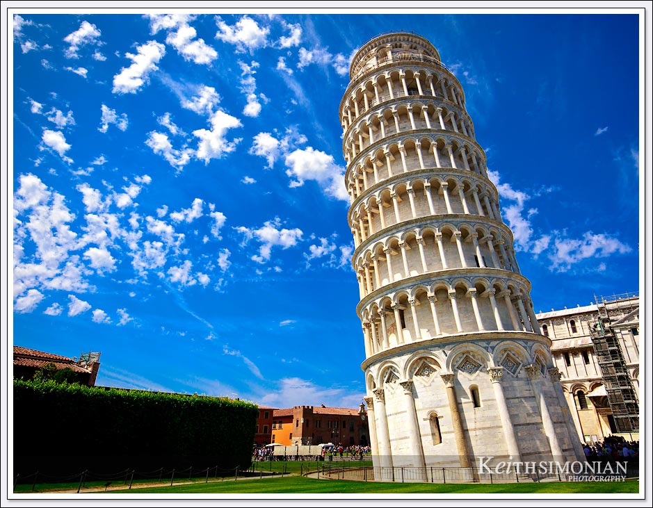 The leaning Tower of Pisa against a blue sky with puffy white clouds - Pisa, Italy