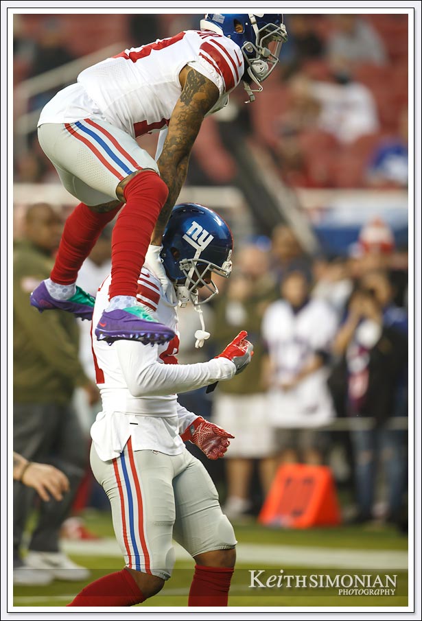 New York Giant Odell Beckham Jr. leaps over a player while leaving the field after pre game warm ups.