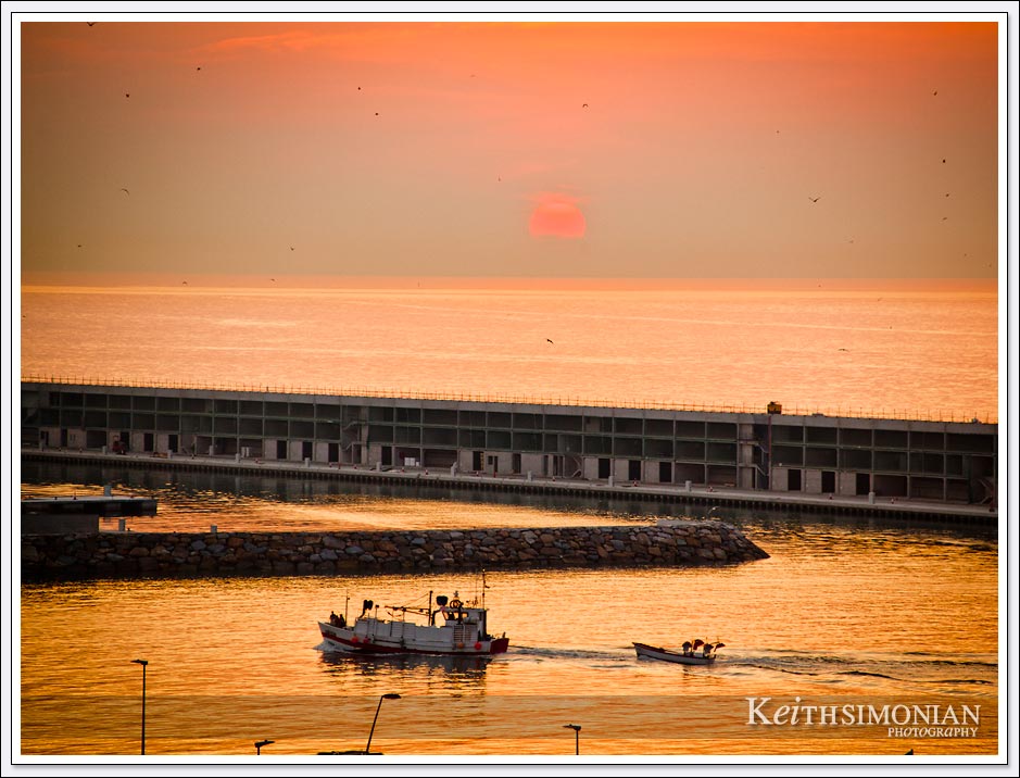 Fishing boat comes back to port during sunrise in Barcelona, Spain