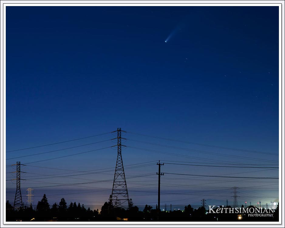 Comet NEOWISE streaks across the sky with power lines in the foreground.
