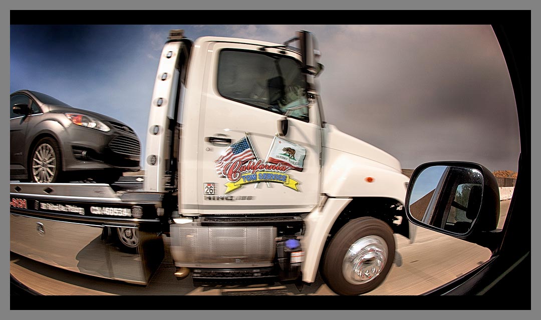 The white California Tow Service truck driving along Highway 4.