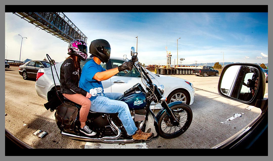 Motorcycle with two people aboard drives Eastbound on Interstate 80 just off the San Francisco - Oakland Bay Bridge.