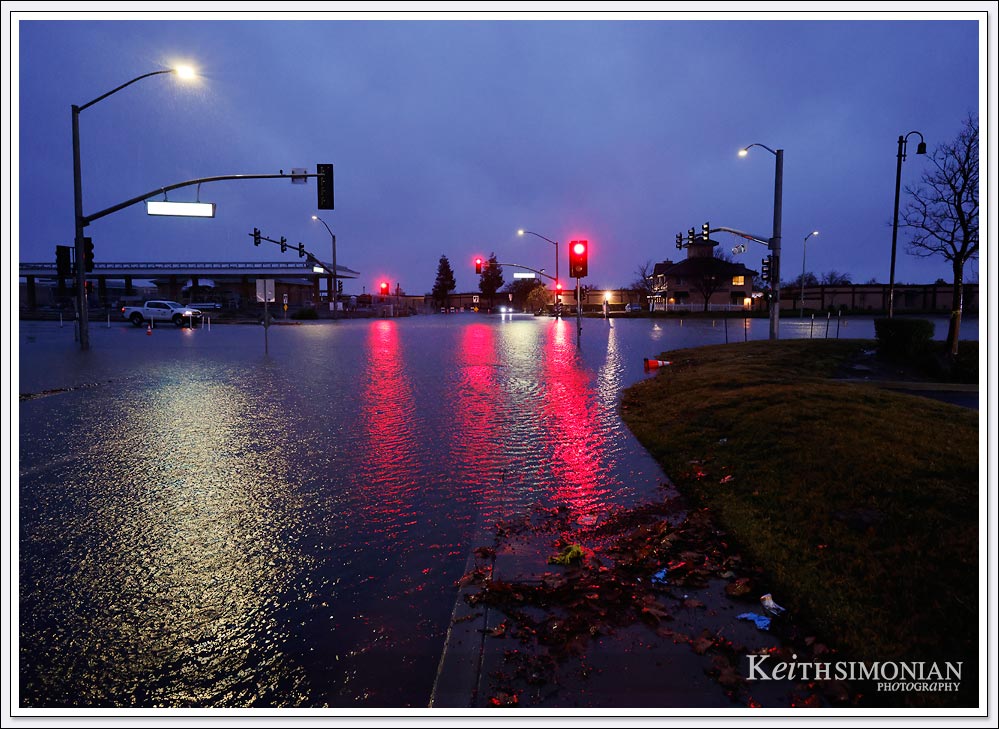 The traffic signals cast a red light across the flooded intersection in Brentwood, CA.