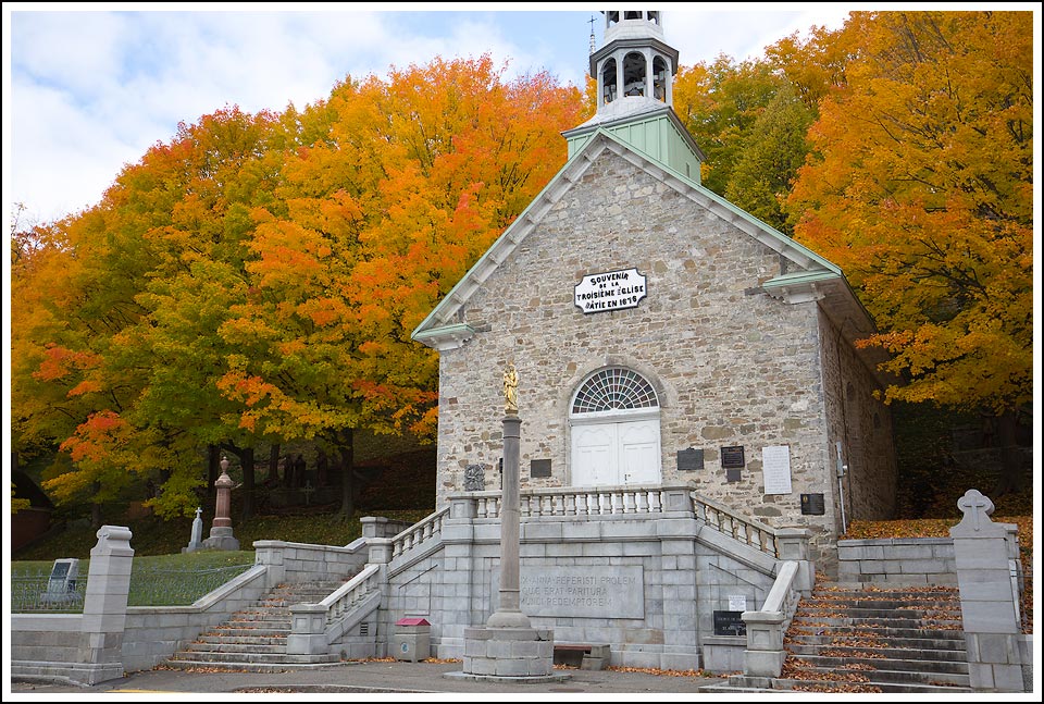 Stone church surrounded by trees with leaves changing colors - Before Photo.
