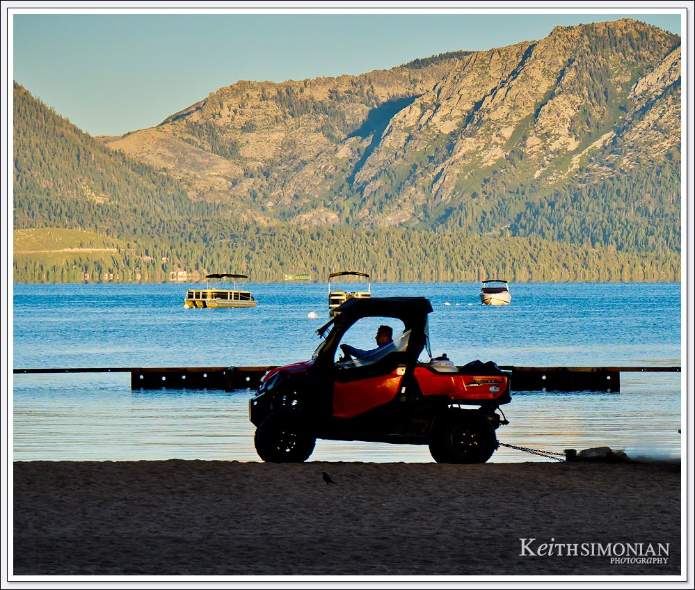 In the early hours a maintenance worker drags the sand at Lakeside beach, Lake Tahoe